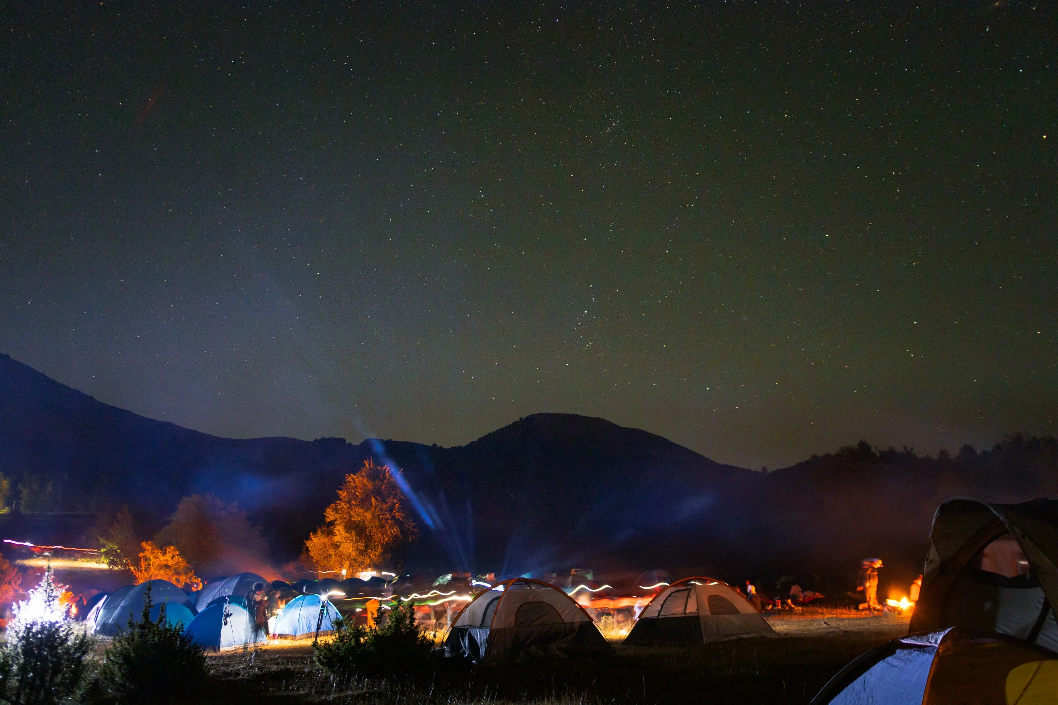 Lit tents under a starry night sky in the Albanian mountains